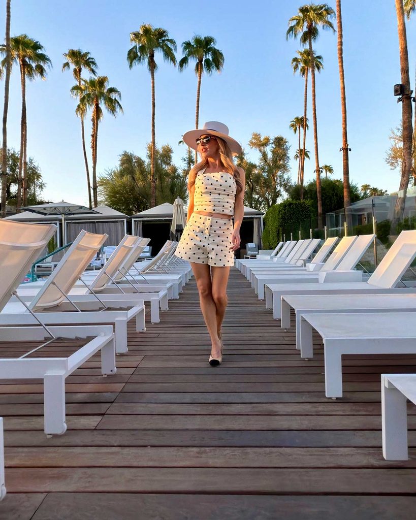 Eric Javits sun hat with UPF 5o sun protection worn by Eve Dawes by the pool wearing a polka dot outfit